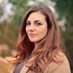 A young woman with long hair smiles confidently for an outdoor portrait session.